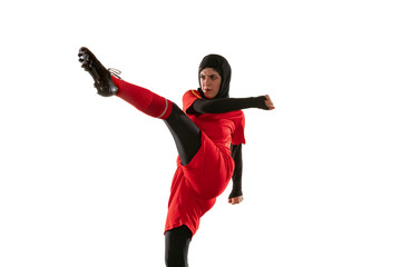 Arabian female soccer or football player isolated on white studio background. Young woman kicking the ball, training, practicing in motion and action. Concept of sport, hobby, healthy lifestyle.
