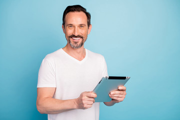 Close-up portrait of nice attractive cheerful cheery guy holding in hands digital ebook reading finance news isolated on bright vivid shine vibrant teal green blue turquoise color background