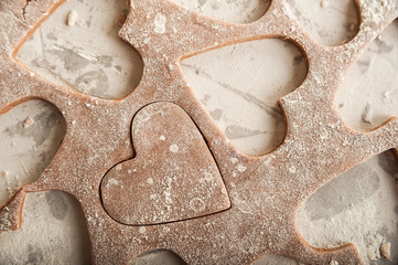 The process of making gingerbread. Flat lay flour heart dough. Texture of the dough for cookies close-up. Gingerbread dough on February 14, flour, rolling pin and copy space.