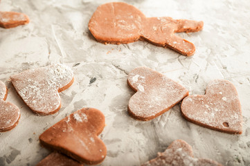 The process of making gingerbread. Flat lay flour heart dough. Texture of the dough for cookies close-up. Gingerbread dough on February 14, flour, rolling pin and copy space.