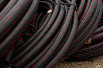Black rubber or plastic pipes with a red lines as a construction material and equipment at building...