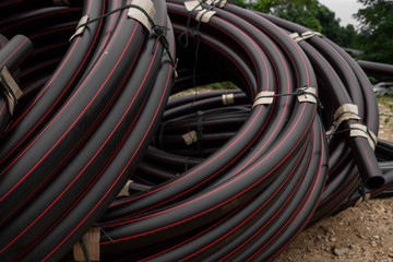 Black rubber or plastic pipes with a red lines as a construction material and equipment at building...