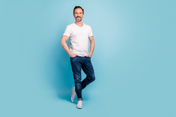 Fototapeta na wymiar Full length body size view of his he nice attractive cheerful cheery mature content guy posing holding hands in pocket isolated on bright vivid shine vibrant teal green blue turquoise color background