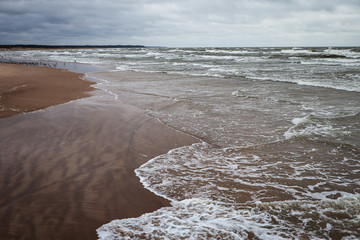 Seaside view of Baltic sea waves on a cloudy and stormy winter day near beach.