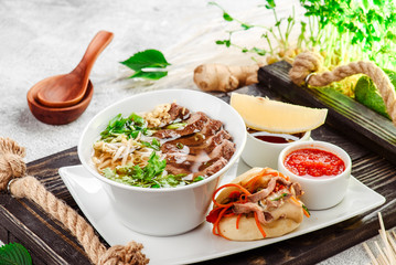 Asian noodle soup, ramen with beef, tofu, vegetables in white plate on a dark restik tray