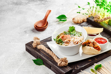 Asian noodle soup, ramen with fish, tofu, vegetables in white plate on a dark restik tray