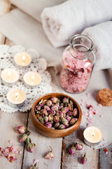 Fototapeta na wymiar Concept of spa treatment with roses. Dry flowers in a bowl, crystals of sea pink salt in bottle, candles as decor. Atmosphere of relax, anti-stress and detox prosedure. Luxury lifestyle. 