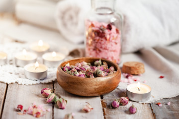 Concept of spa treatment with roses. Dry flowers in a bowl, crystals of sea pink salt in bottle,...