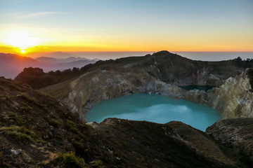 Sunrise over the Kelimutu volcanic crater lakes in Moni, Flores, Indonesia. Skyline is bursting with orange. Turquoise color of the lake. Golden hour colours the surroundings. Beauty of the nature