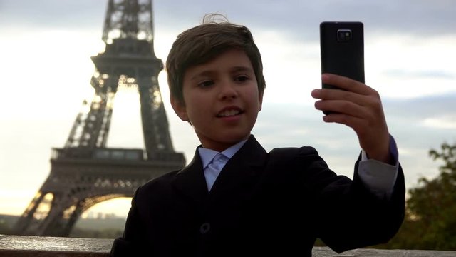 Beautiful teenager boy is making selfie on the phone on the background of the Eiffel tower, Paris, France