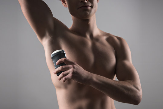 Cropped View Of Shirtless Man Holding Deodorant Near Underarm Isolated On Grey