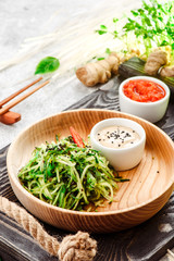 Pan-Asian food. Vegetable salad with chuka, cucumber and sesame seeds on round wooden plate