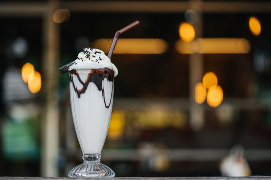 Vanilla chocolate milkshake on a cafe bar with beautiful bokeh of street lamps.