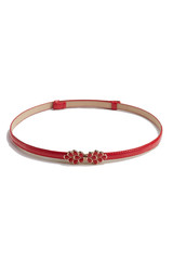 Naklejka premium Subject shot of a thin belt made of red leather and decorated with a figured buckle in the form of golden drops with red jeweller's enamel. The stylish belt is isolated on the white background.