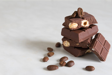 pieces of chocolate with hazelnuts and coffee beans on a marble table
