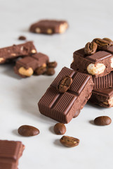 pieces of chocolate with hazelnuts and coffee beans on a marble table