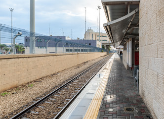 Several travelers await the train on the empty platform of the Mirkaz Shmona railway station in Haifa, Israel