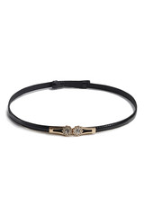 Fototapeta premium Subject shot of a thin belt made of black patent leather and decorated with a golden figured buckle with crystal flowers. The stylish belt is isolated on the white background.