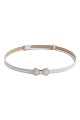 Subject shot of a thin belt made of white patent leather and decorated with a figured buckle in the form of a white bow-knot in golden setting. The stylish belt is isolated on the white background.