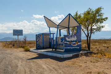 Fototapeta na wymiar empty bus stop on the road, waiting place for the bus, Issyk-Kul Lake, Kyrgyzstan
