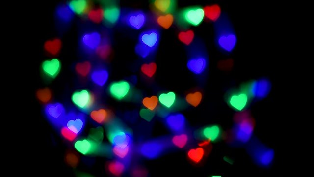 Multi-colored lights in the shape of hearts glow on a black background.