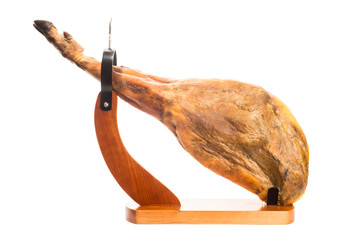 Whole Iberian ham leg in a wooden ham stand isolated