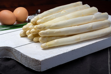 Bunch of fresh uncooked white asparagus and boiled eggs, new harvest