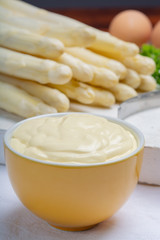 White hollandaise sauce in bowl, traditional sauce for dishes with cooked white asparagus