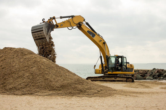 xcavator digs sand on the beach of the Bulgarian sea coast. Protecting the territory for winter from flooding.