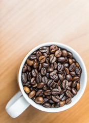 bright clean close up shot of a white coffee mug and coffee beans wooden background top down view