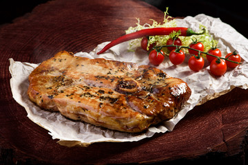 T-Bone steak serving with vegetables on a dark wooden board. close up. space