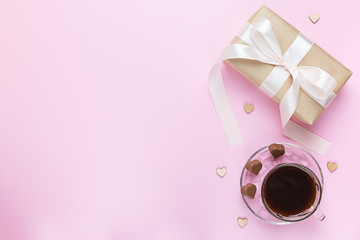 Banner of Valentine's Day. A Cup of coffee, a gift box and a heart-shaped chocolate on a pink background.