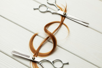 Dollar sign made of curl hair. Expensive hairstyle or hairdresser. White wood background with hair...