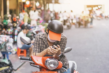 Male tourist parked a motorbike on the roadside to use his smartphones to find routes in the city.