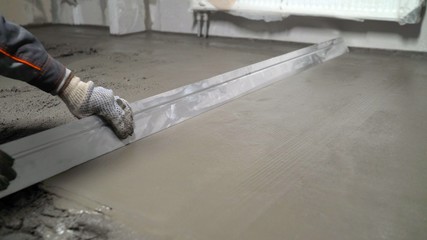 The process of leveling floors in the apartment with a solution. Construction work, concrete cement...