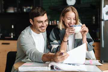 Image of happy young businesslike man and woman doing paperwork in cafe