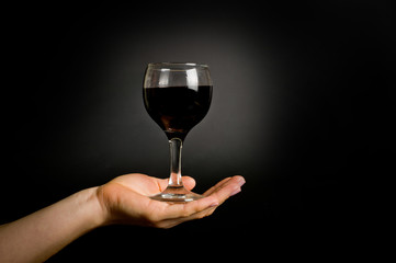 .female hand with a glass of wine on a dark background