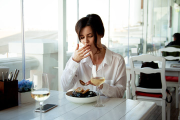 Adult beautiful woman sit in elite restaurant with a beautiful view of the sea, her order seafood...