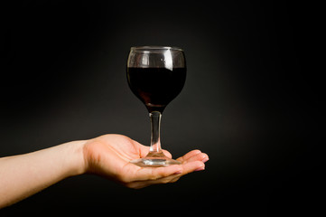 .female hand with a glass of wine on a dark background