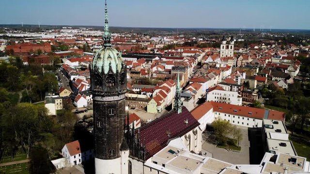 Cinematic aerial shot of an old church with a beautiful city in backround