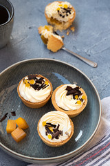 homemade shortbread tartlets or cupcakes with delicate cream and orange jam, decorated with chocolate chips. natural sweets concept. cozy tea party