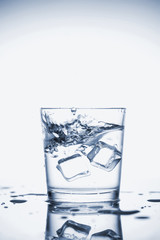 Clear mineral water splashes in a glass with ice.