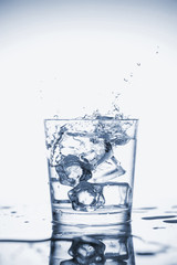 Clear mineral water splashes in a glass with ice.
