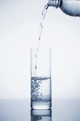 Clear mineral water is poured into a glass with ice.
