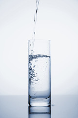 Clear mineral water is poured into a glass with ice.