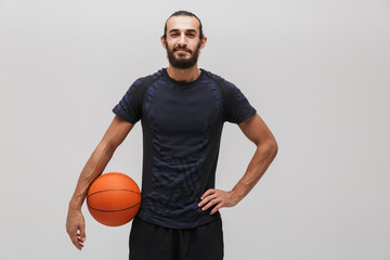 Obraz premium Image of young pleased man posing with basketball and smiling