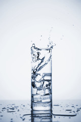 Clear mineral water splashes in a glass with ice.