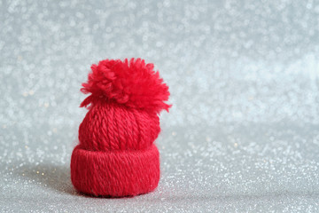 Red knitted small hat isolated on a Silvery bokeh background. New Year card. Free space for inscription.