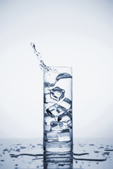 Clear mineral water splashes in a glass with ice.