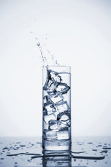 Clear mineral water splashes in a glass with ice.